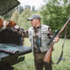 A shot of a hunter with riffle and his dog preparing for a hunt.